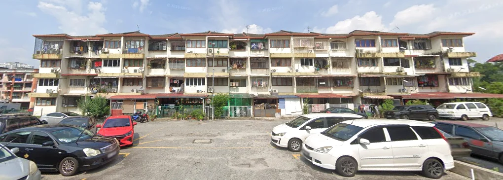 Exterior type: low-rise apartment block; features: 3-storey building, balconies with railings, multiple windows on each floor, exposed concrete facade, parking lot in front, various parked cars, surrounding greenery, laundry hanging on balconies; style: traditional.
